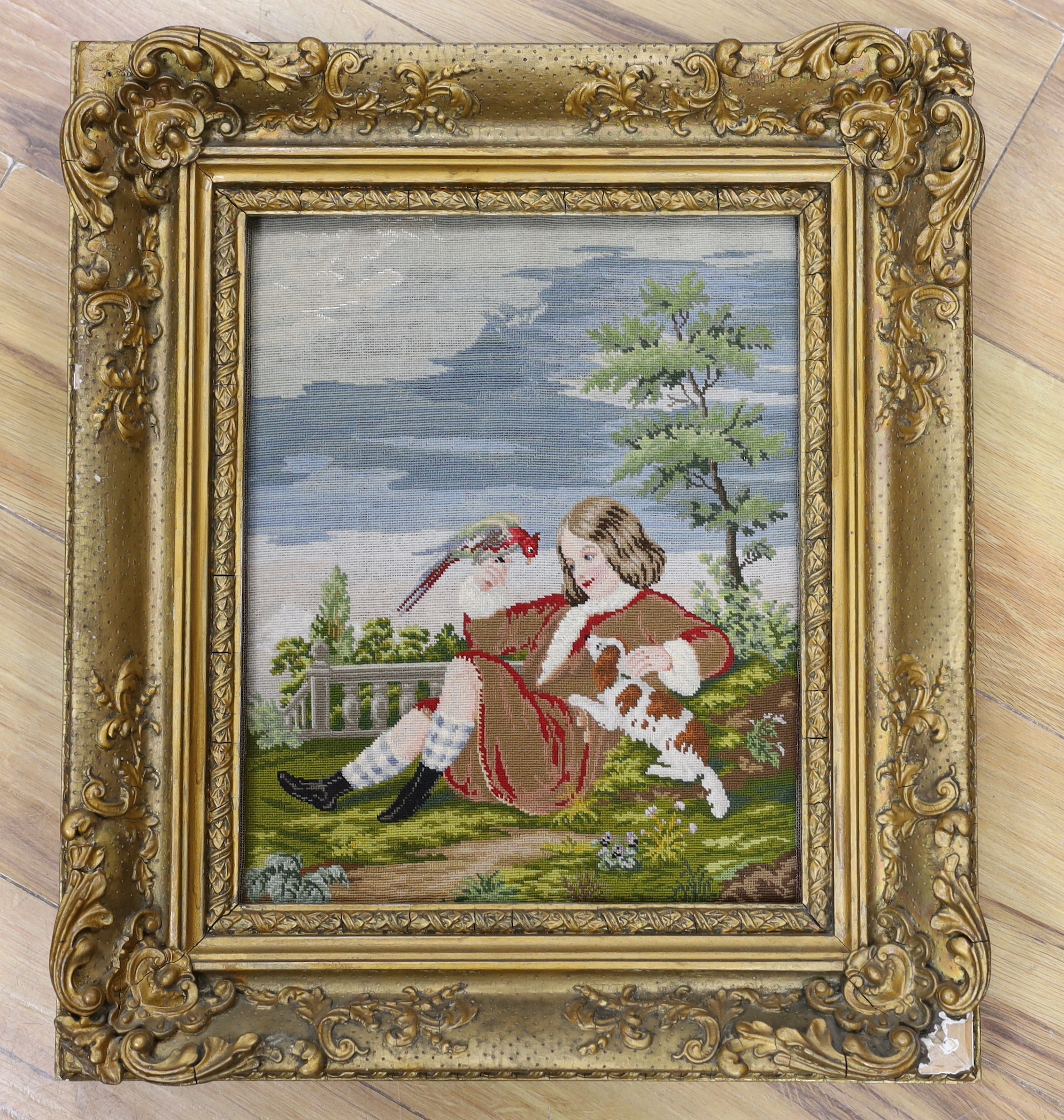 A framed Victorian Berlin needlework panel, of the Duke of Northumberland as a boy of 12 years (in 1751) holding a pet parrot and King Charles Spaniel, label verso, 26cm wide x 34cm high